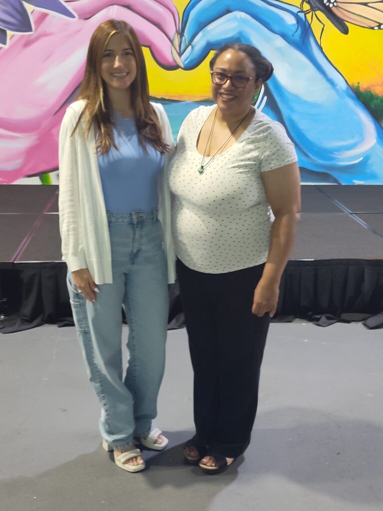 SFWN Program Director Kayla Calafiore and massage therapist April Heath standing in front of a colorful mural