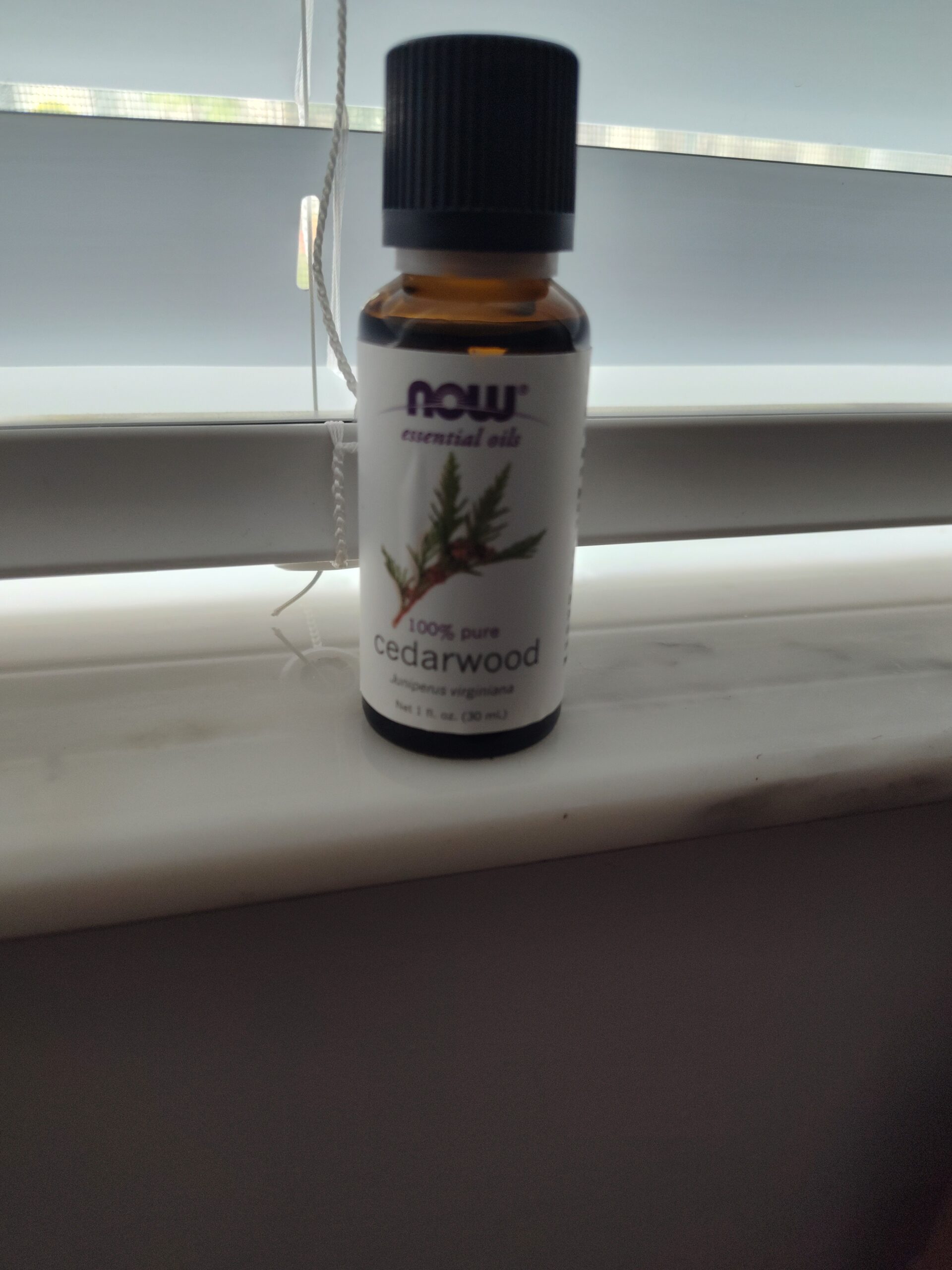 Bottle of NOW cedarwood essential oil on windowsill