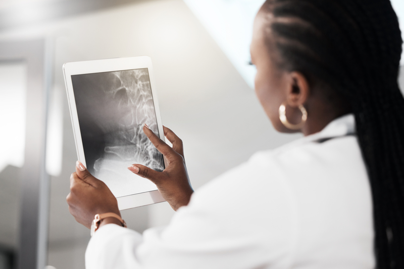 Black female chiropractor looking at x-ray of spine